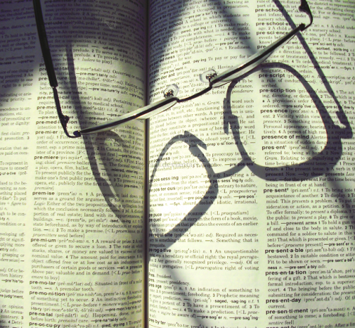 A picture of an open dictionary page with eyeglasses on top.